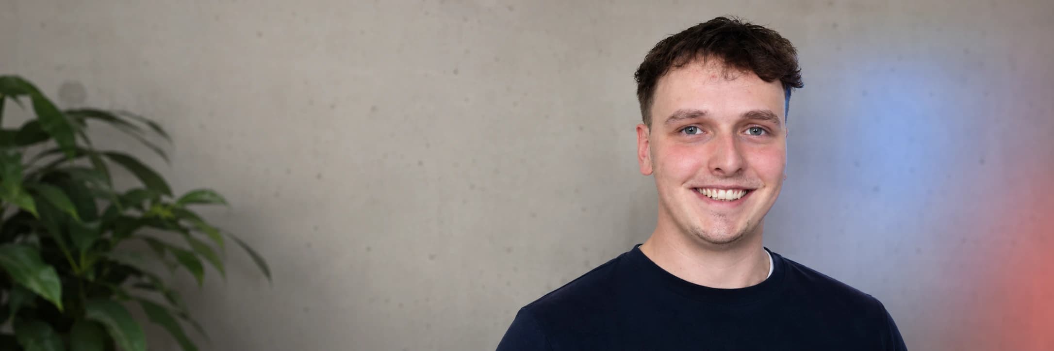 Konrad Mayer vor einer hellen Wand mit Pflanzen und farbigem Licht